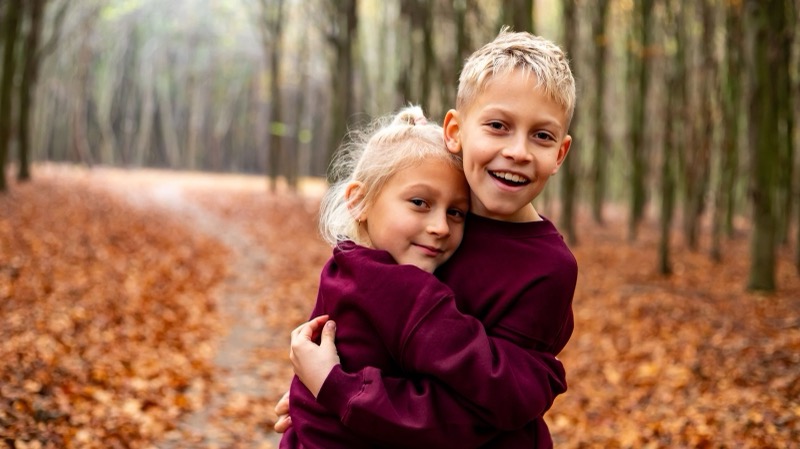 Broer en zus knuffelen in het herfstbos