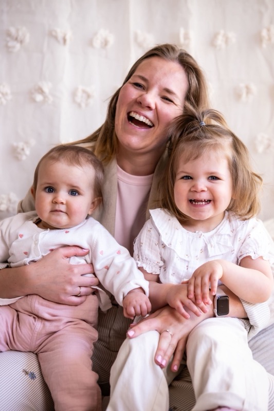 Lachende mama met twee kleine meisjes op schoot