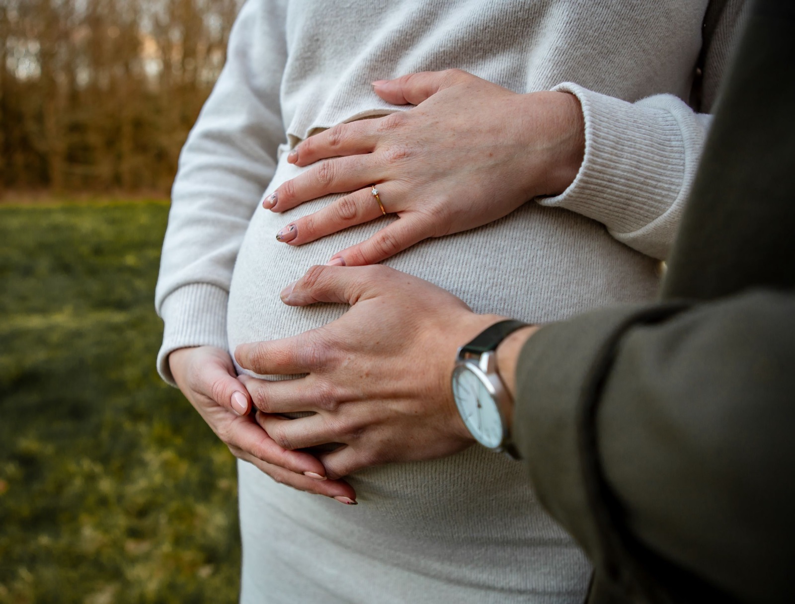 Handen van de aanstaande ouders op de zwangere buik