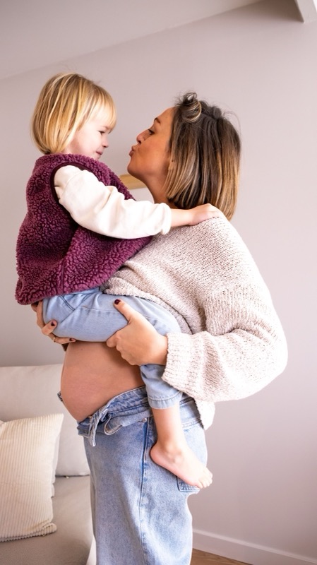 Zwangere mama met haar dochtertje op de arm