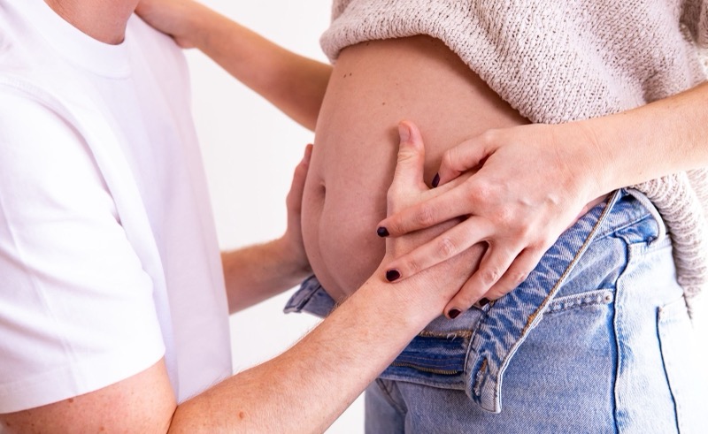 Handen van mama en papa op de babybuik