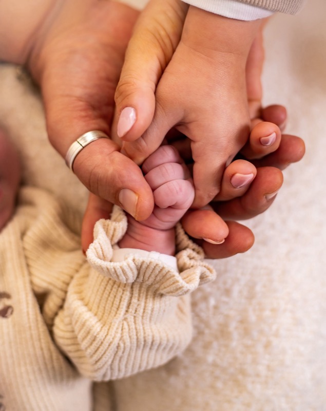 Babyhandje rust in de handen van mama en papa