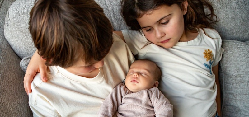 Broer en zus bewonderen de newborn baby