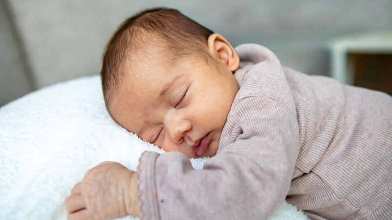 Newborn baby slaapt op een wit kussen