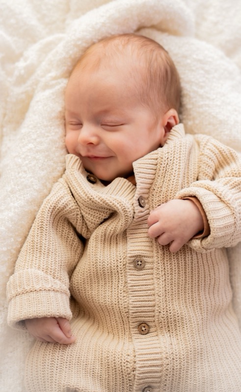 Newborn baby glimlacht in de slaap in een gebreid pakje
