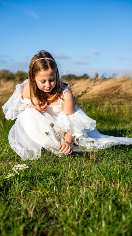 Meisje in een wit kleedje zit in het gras