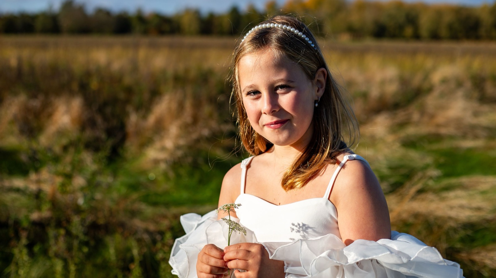 Meisje zit in het hoge gras bij gouden licht