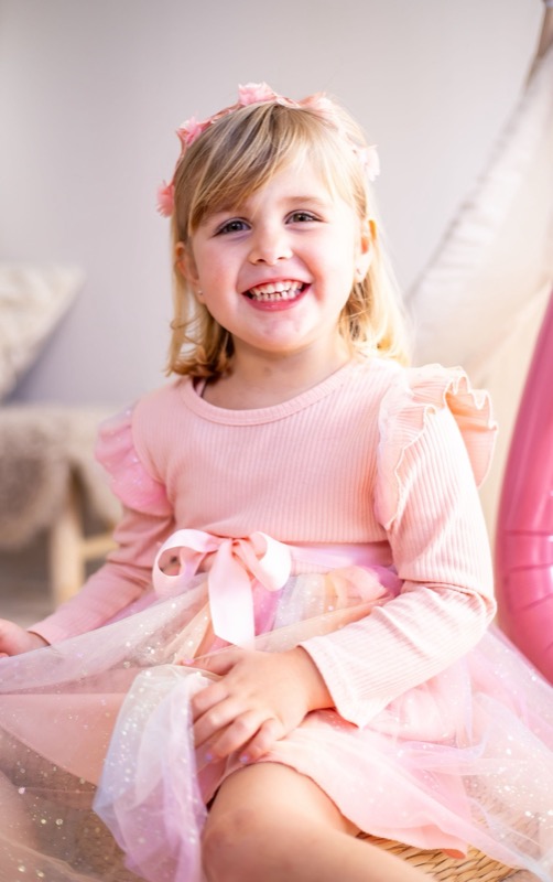 Lachend meisje in een roze feestjurk