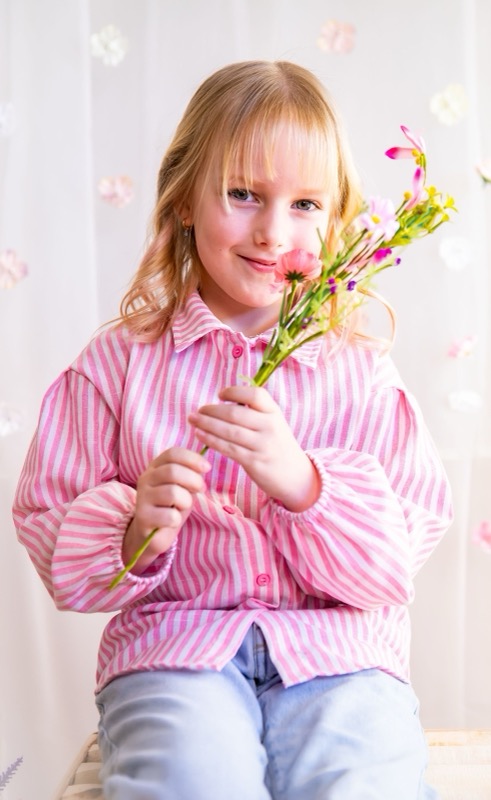 Meisje in een roze blouse met veldbloemen, portret in de studio