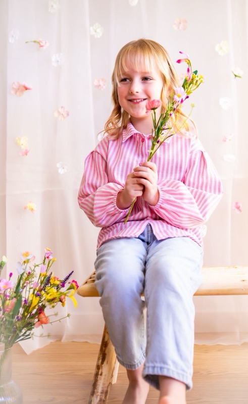 Meisje zit op een krukje met een boeketje bloemen